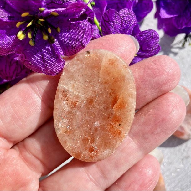 N�rbillede af en oval solsten bekymringssten, ogs� kaldet worry stone, holdt i en h�nd.
