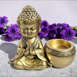 Gylden fyrfadsstage med en lille thailandsk Buddha figur i bedende stilling.