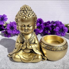 Gylden fyrfadsstage med en lille thailandsk Buddha figur i bedende stilling.