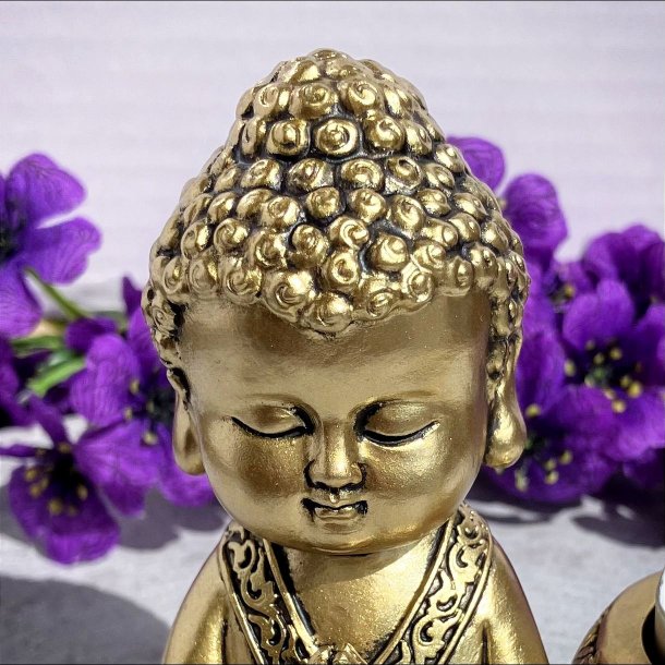 Detaljeret t�t billede af hovedet p� den lille gyldne Buddha fyrfadsstage.