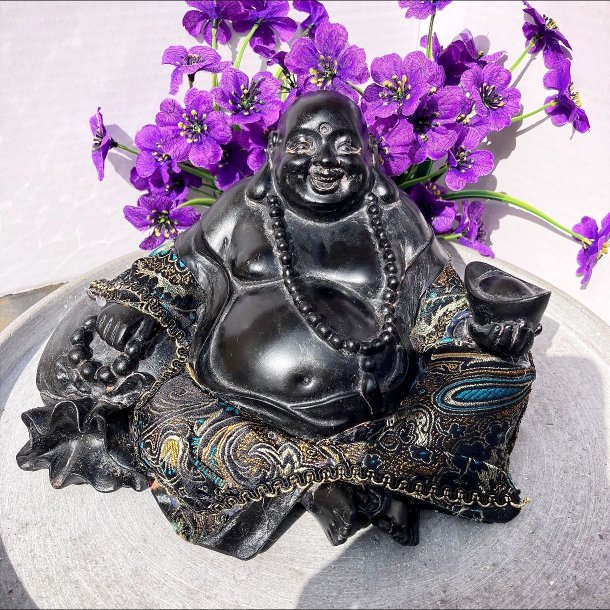 Glad, siddende lykkebuddha i sort polyresin med farverige m�nsterdetaljer, perlek�de og en kinesisk guldbarre i h�nden.