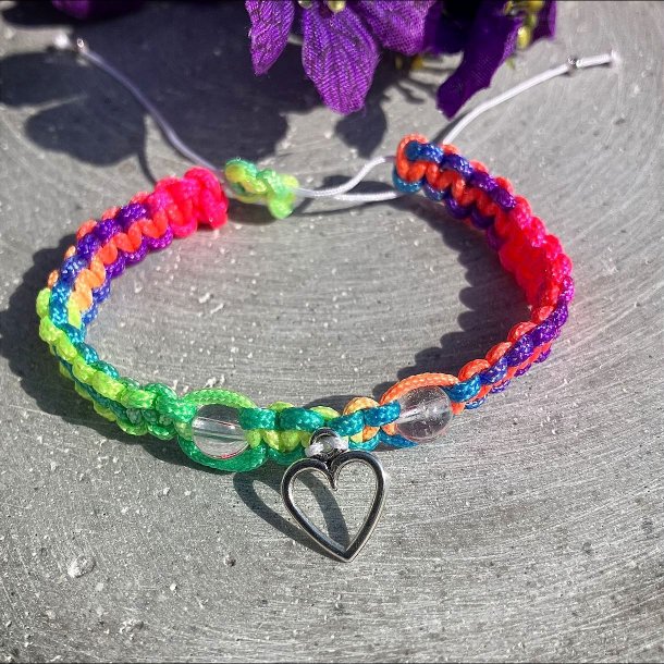 Armbnd, hndlavet af Krystal Oasen med bjergkrystal (6,5 mm) og slvfarvet hjerte charm. Justerbar regnbuefarvet og hvid nylonsnor, ca. 7 mm bredt.
