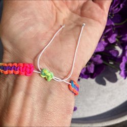 Armbnd, hndlavet af Krystal Oasen med bjergkrystal (6,5 mm) og slvfarvet hjerte charm. Justerbar regnbuefarvet og hvid nylonsnor, ca. 7 mm bredt.