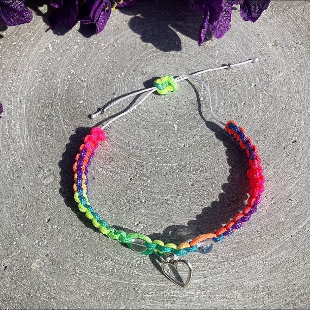 Armbnd, hndlavet af Krystal Oasen med bjergkrystal (6,5 mm) og slvfarvet hjerte charm. Justerbar regnbuefarvet og hvid nylonsnor, ca. 7 mm bredt.