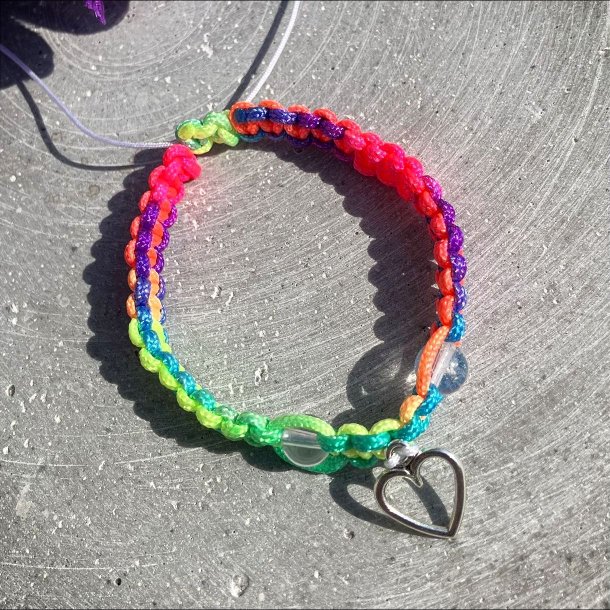 Armbnd, hndlavet af Krystal Oasen med bjergkrystal (6,5 mm) og slvfarvet hjerte charm. Justerbar regnbuefarvet og hvid nylonsnor, ca. 7 mm bredt.