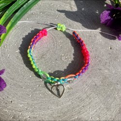 Armbnd, hndlavet af Krystal Oasen med bjergkrystal (6,5 mm) og slvfarvet hjerte charm. Justerbar regnbuefarvet og hvid nylonsnor, ca. 7 mm bredt.