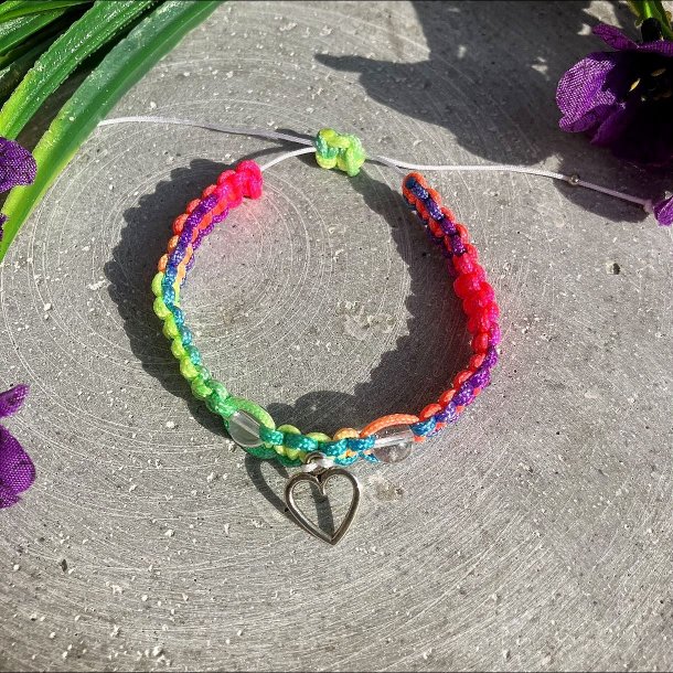 Armbnd, hndlavet af Krystal Oasen med bjergkrystal (6,5 mm) og slvfarvet hjerte charm. Justerbar regnbuefarvet og hvid nylonsnor, ca. 7 mm bredt.
