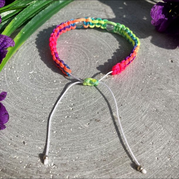 Armbnd, hndlavet af Krystal Oasen med bjergkrystal (6,5 mm) og slvfarvet hjerte charm. Justerbar regnbuefarvet og hvid nylonsnor, ca. 7 mm bredt.