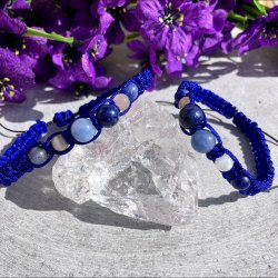 To h�ndlavede knyttet krystalarmb�nd i bl� snor med krystaller af angelit, lapis lazuli, m�nesten og sodalit, placeret p� en bjergkrystal