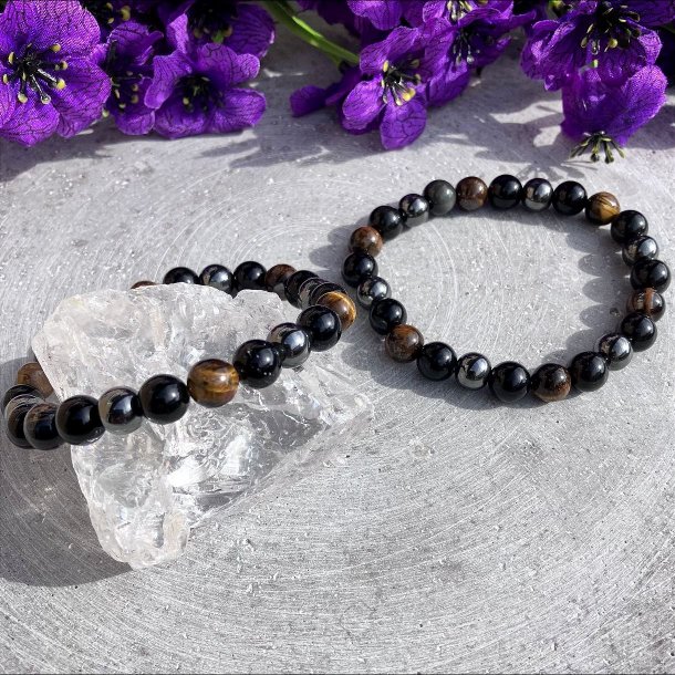 To krystalarmb�nd med �gte tiger�je, obsidian og h�matit perler p� en gr� stenbaggrund.