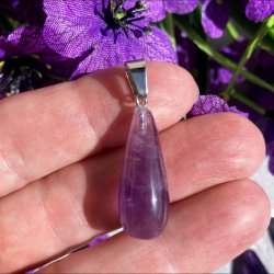 N�rbillede af et dr�beformet krystalvedh�ng med poleret ametyst. Krystallen viser naturlige skift mellem lyse og m�rke violette farvetoner.