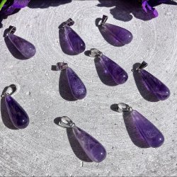 En samling af polerede ametyst dr�be vedh�ng for at vise de naturlige variationer i de lilla krystallers nuancer