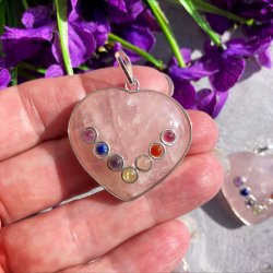 N�rbillede af et hjerteformet rosakvarts vedh�ng med chakra sten holdt i h�nden med lilla baggrund.